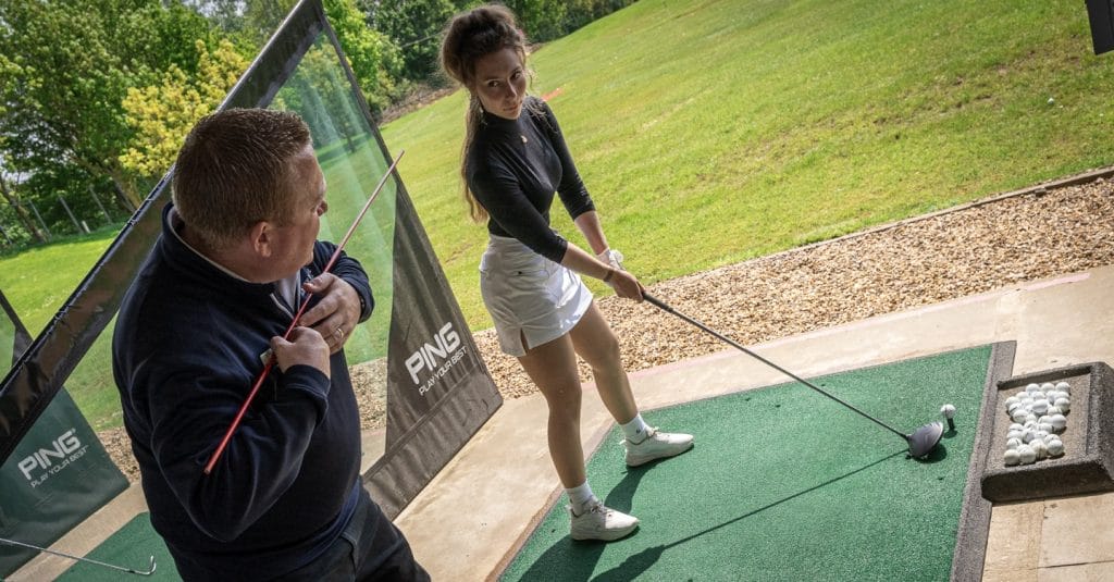 golf coach teaching female about golf swing during a golf lesson in milton keynes